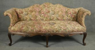 A 19th century style shaped back sofa in tapestry upholstery on carved scrolling apron and