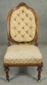 A Victorian walnut nursing chair with floral carved back rail and buttoned upholstery on tapering