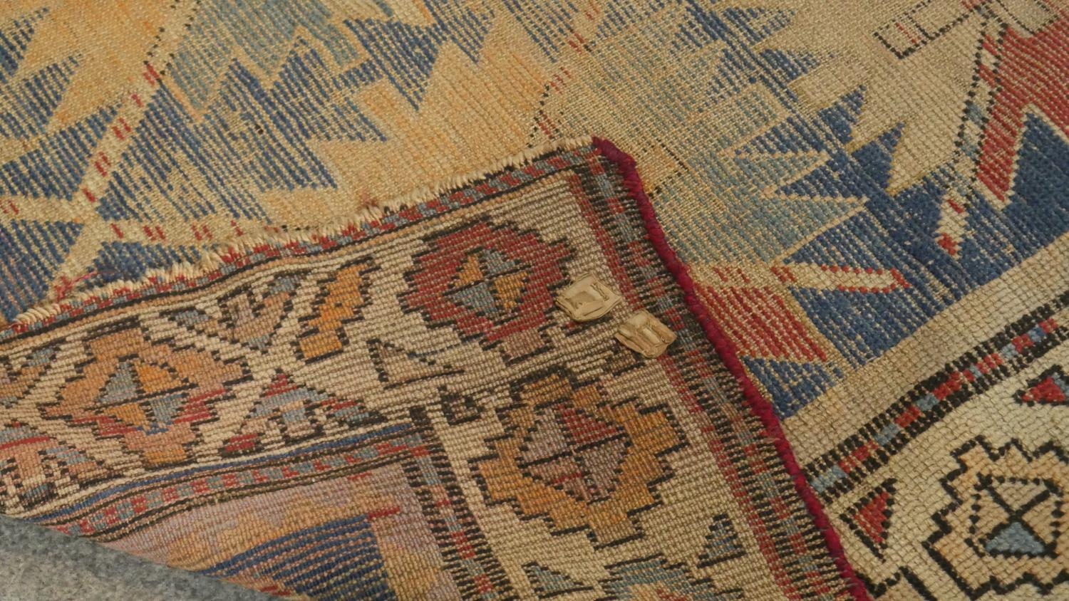 A Kazak rug with repeating star medallions on a sapphire ground within stylised multiple borders. - Image 3 of 3