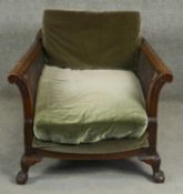An early 20th century Georgian style mahogany framed bergere armchair on squat shell carved cabriole