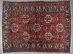 A Persian Hamadan rug with repeating floral design across the burgundy field. L.220 W.150cm