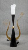 A mid century black and gilded abstract table lamp with gold tendrils and frosted conical shade. H.