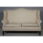 A Georgian style mahogany framed wing back two seater sofa in diamond pattern ivory upholstery on