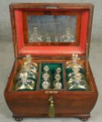 A Regency flame mahogany sarcophagus form decanter box fitted with six hand gilded decanters and