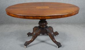 A 19th century walnut tilt top dining table with satinwood Arabesque inlaid central cartouche. H.