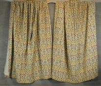 A fair of lined embroidered stylised floral and foliate tapestry design curtains on a cream