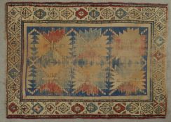 A Kazak rug with repeating star medallions on a sapphire ground within stylised multiple borders.