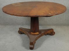 An early 19th century flame mahogany tilt top dining table with gadrooned edge on platform base. H.