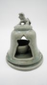 A celadon glaze ceramic tea light holder with foo dog finial. H.17cm