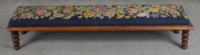 A Victorian mahogany hearth stool in floral tapestry upholstery on bobbin turned supports. H.20 L.