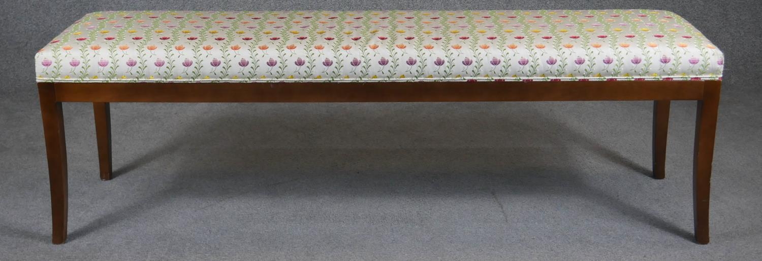 A contemporary window seat in piped floral upholstery on slender sabre supports. H.50 L.160 D.40cm