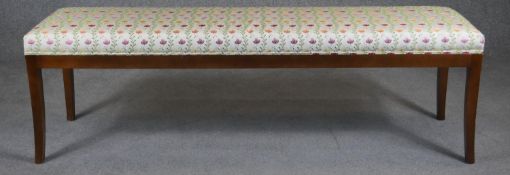 A contemporary window seat in piped floral upholstery on slender sabre supports. H.50 L.160 D.40cm