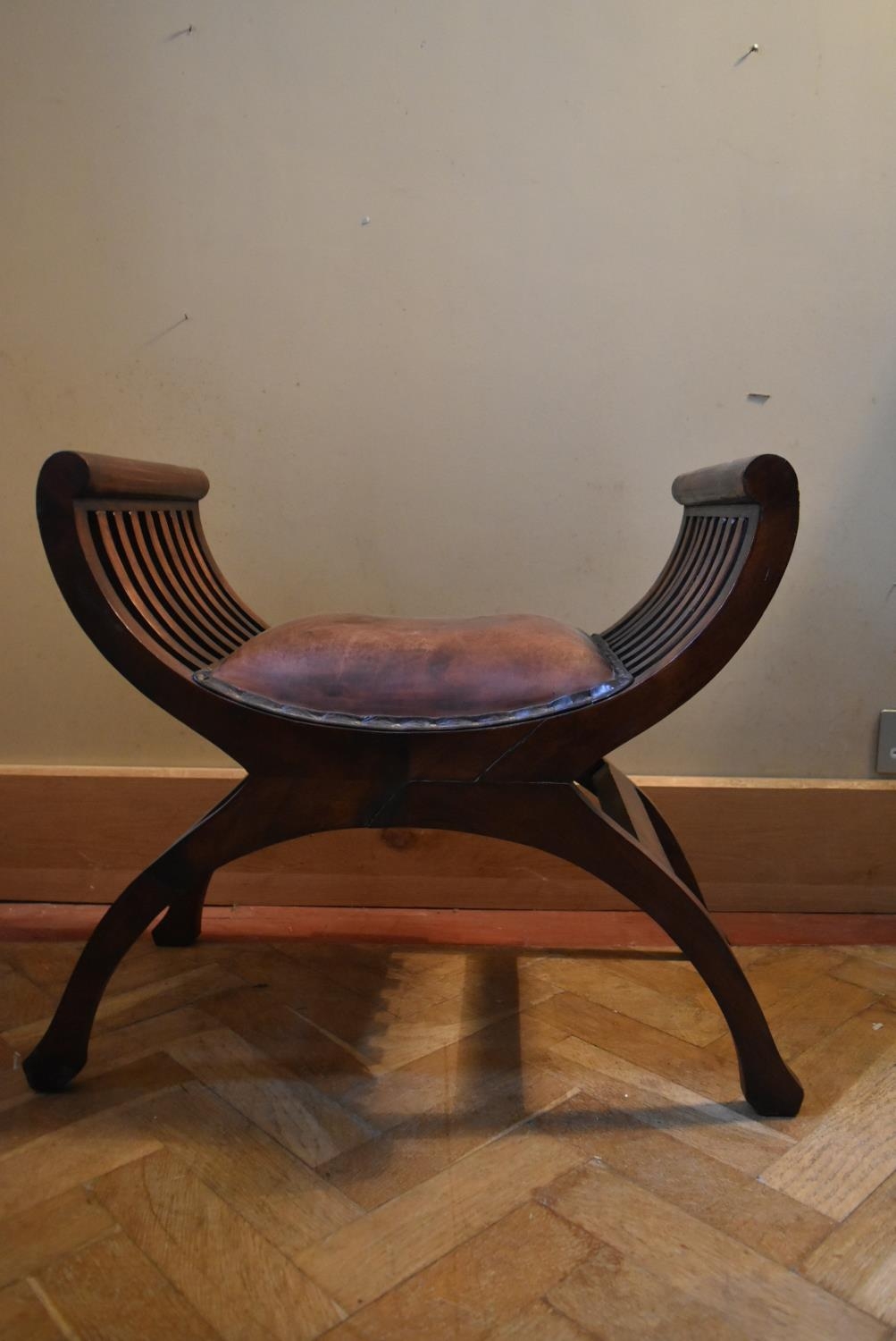 A mahogany X frame stool in leather upholstery. H.58 W.64 D.36cm
