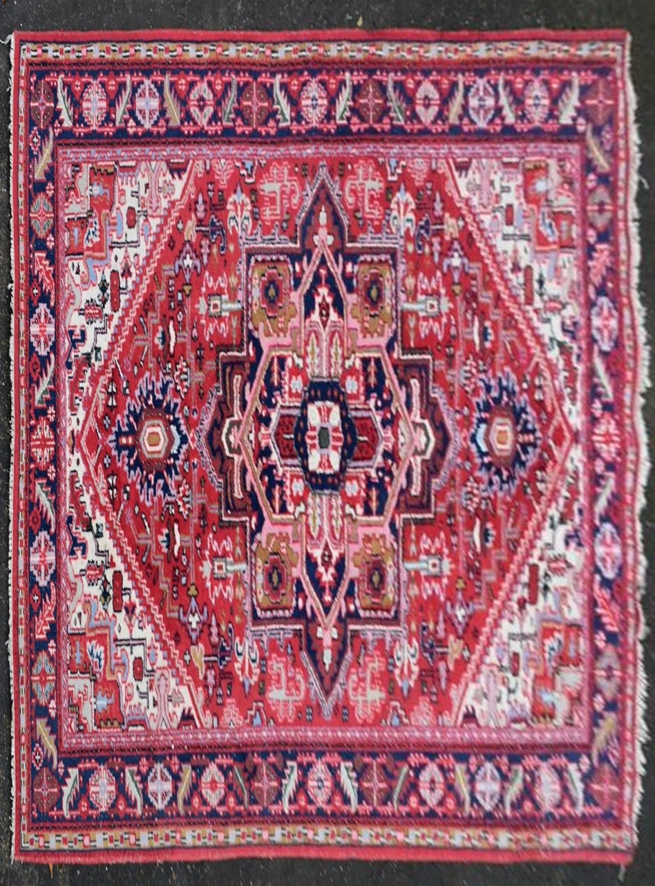 A Persian Heriz carpet with central star medallion on a burgundy ground within a foliate multiple