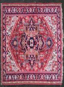 A Persian Heriz carpet with central star medallion on a burgundy ground within a foliate multiple