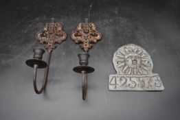 A pair of vintage cast iron wall mounted candle holders with relief Classical mask motifs along with