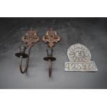 A pair of vintage cast iron wall mounted candle holders with relief Classical mask motifs along with