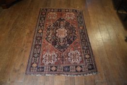 A Shiraz rug on russet ground with a geometric central motif. H.188 W.119cm