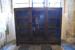 A mid century oak dwarf library bookcase with triple glazed drawers enclosing shelves on square