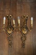 A pair of carved gilt wood Adam style twin branch wall sconces with ribbon and husk swag decoration.