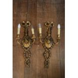 A pair of carved gilt wood Adam style twin branch wall sconces with ribbon and husk swag decoration.