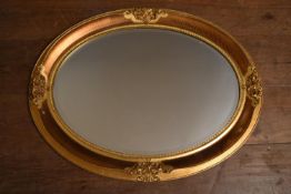 A contemporary oval wall mirror in gilt and ebonised floral frame. H.66 W.86cm