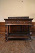 A mid century Jacobean style oak serving table with carved back above a pair of frieze drawers on