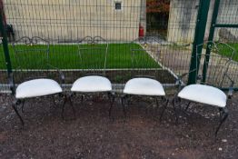 A set of four metal framed dining chairs with upholstered seats.