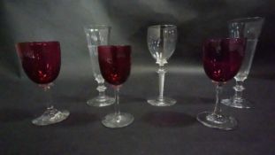 Three Victorian cranberry glass wine glasses along with a pair of antique petal facet liqueur