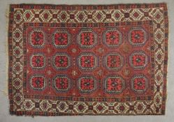A Turkomen rug with repeating medallions on a burgundy ground within stylised borders. L.200 W.135cm