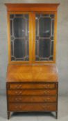 An Edwardian quarter veneered mahogany bureau bookcase with leather lined fall front and fitted