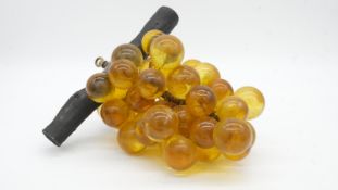 A vintage bunch of amber lucite grapes mounted on a wooden branch. H.18cm