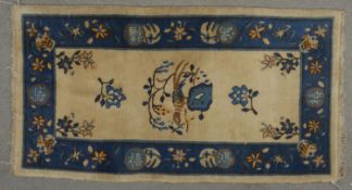 A antique Chinese rug with bird and flower decoration on a fawn ground within a floral sapphire
