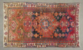 A Persian Loristan rug with repeating serrated medallions within stylised borders. L.215 W.128