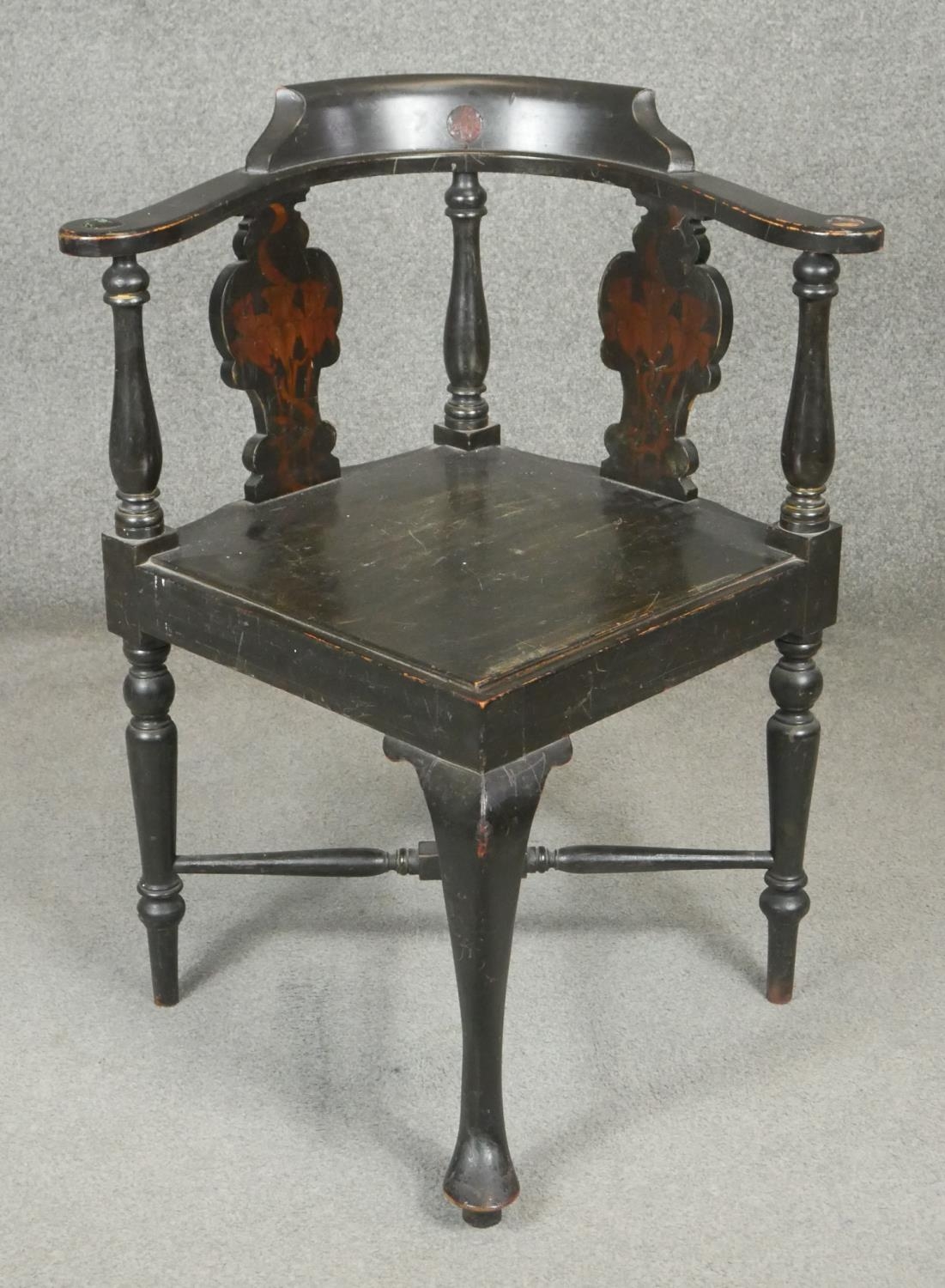 An ebonised corner armchair with Arts and Crafts style pokerwork daffodil decoration to the back