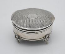 A sterling silver engine decorated round trinket box with red velvet interior, circular cartouche to