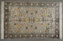 A Kasmir silk rug with scrolling foliate decoration across the field within floral multiple borders.
