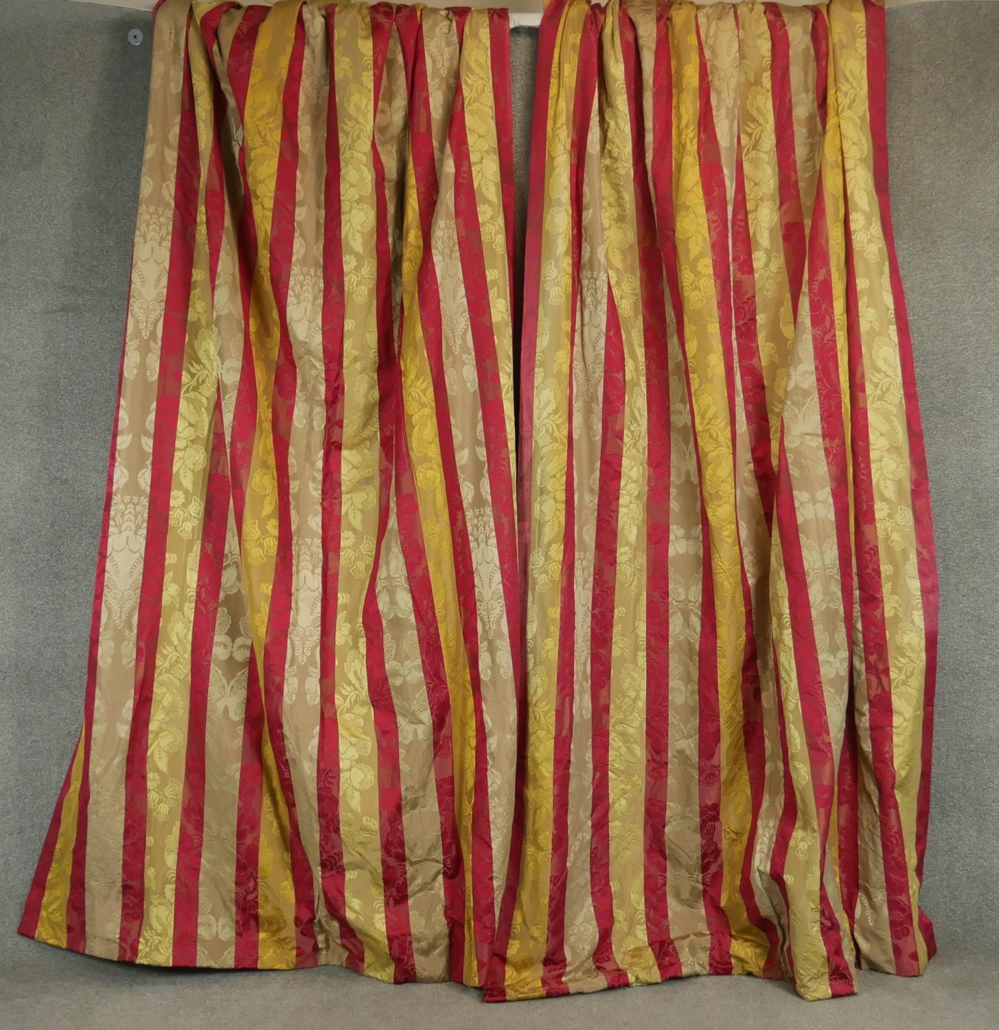 A pair of silk mix red, gold and cream striped lined curtains with a stylised floral and foliate