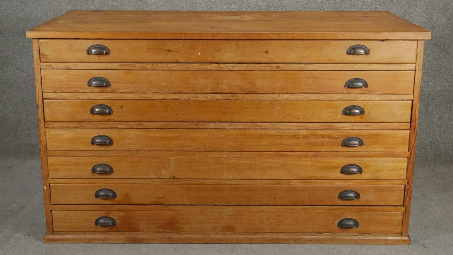 A vintage pine architect's plan chest of seven drawers with brass cup handles. H.94 W.155 D.77cm