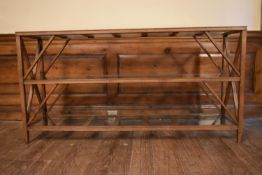 An X framed teak console table with three plate glass tiers. H.72 W.140 D.33cm
