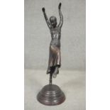 An Art Deco style spelter sculpture of a female dancer in period clothing with headdress, on a
