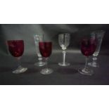 Three Victorian cranberry glass wine glasses along with a pair of antique petal facet liqueur