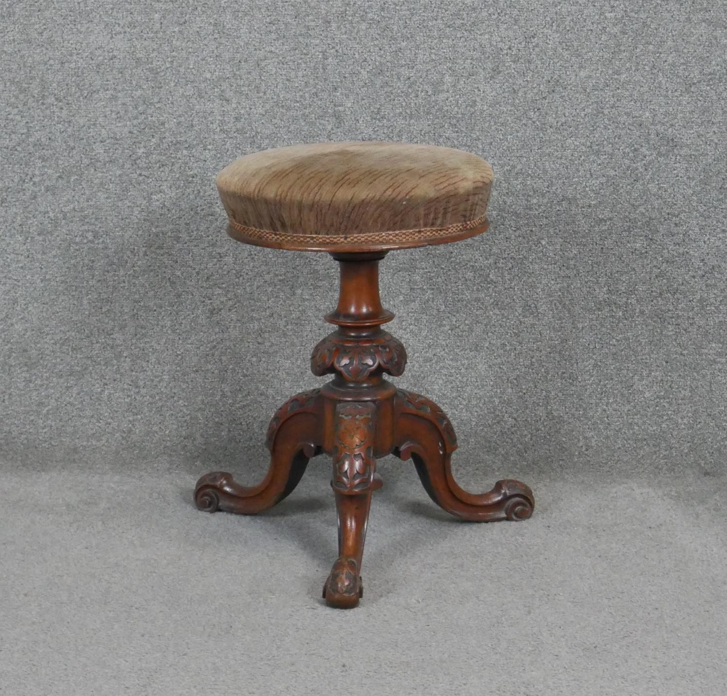 A Victorian carved walnut revolving adjustable piano stool on tripod cabriole base. h50 d45