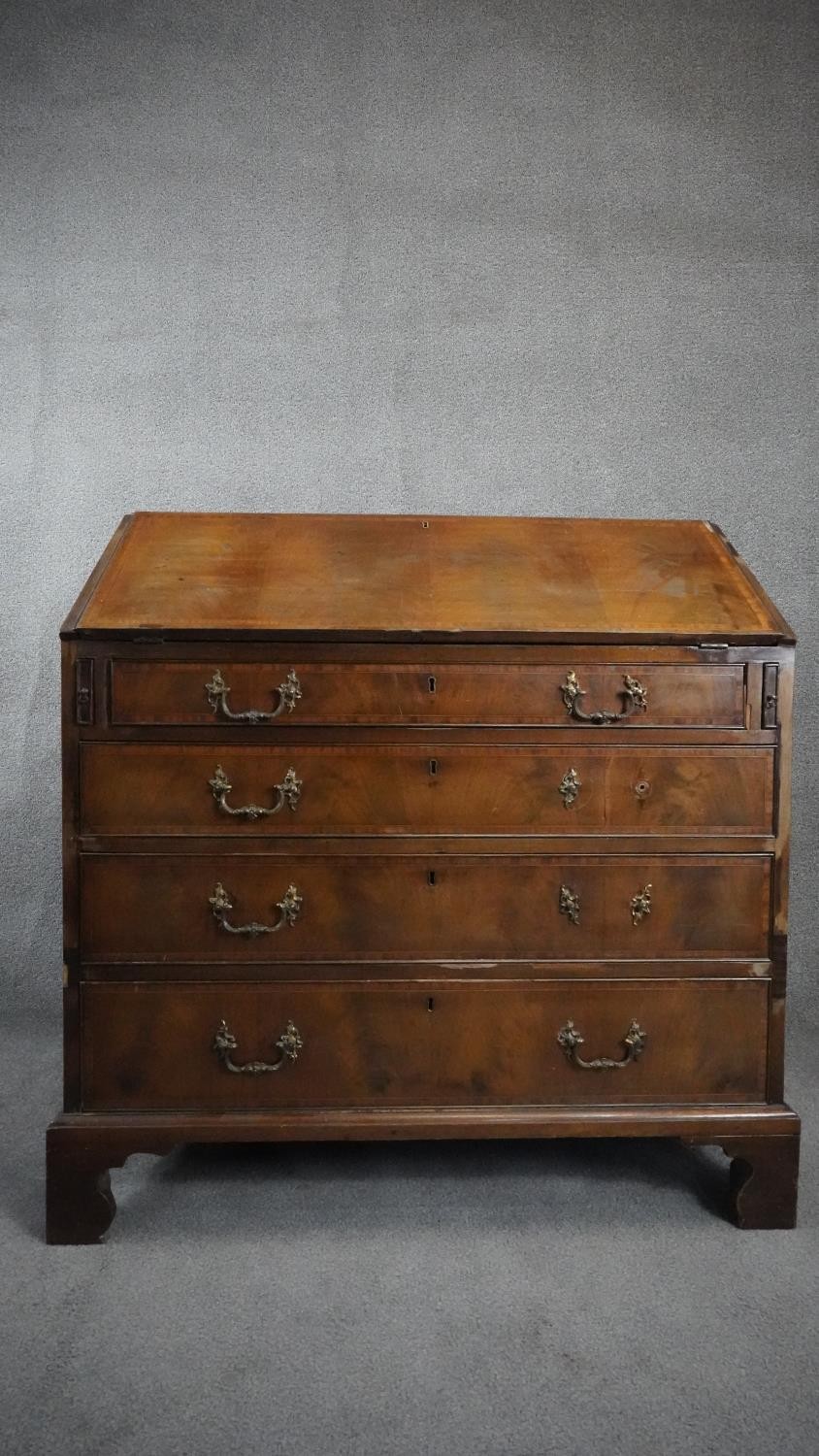 A Georgian flame mahogany and crossbanded bureau with fitted interior on shaped bracket feet. H.