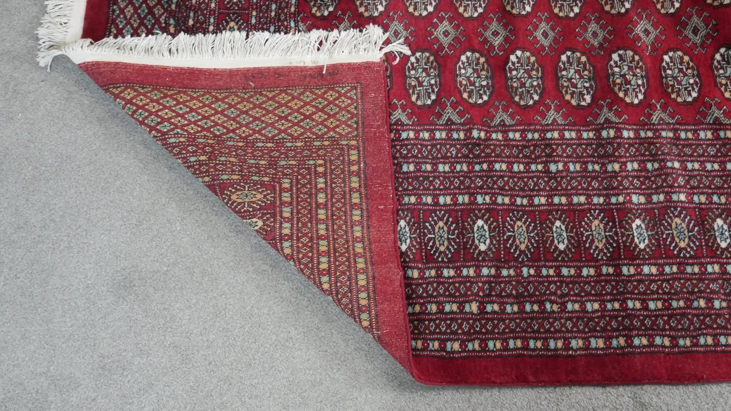 A Bokhara carpet with repeating gul motifs on a burgundy ground within multiple borders. L.358 W. - Image 5 of 5