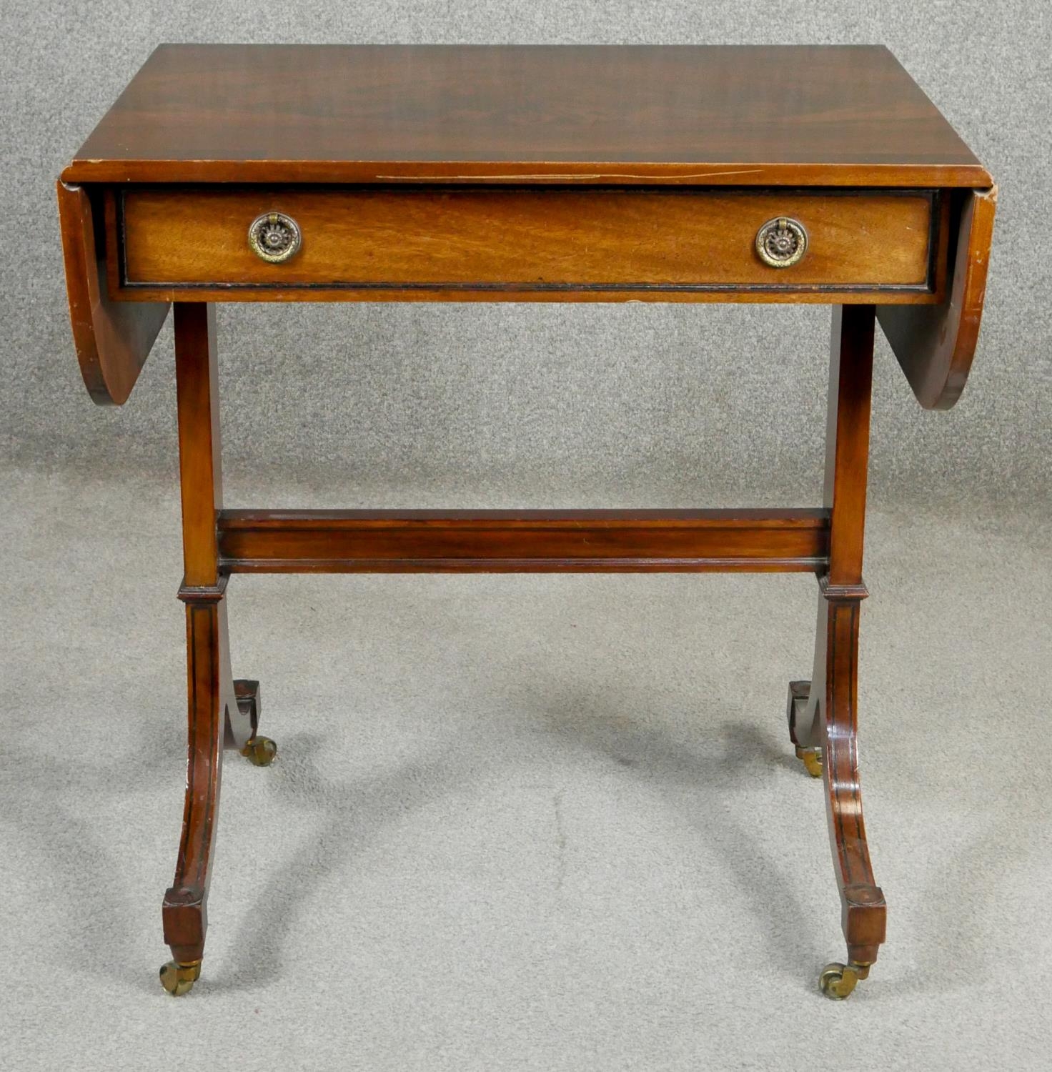 A Regency style flame mahogany and crossbanded sofa table on ebony strung swept supports resting