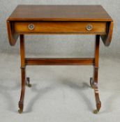 A Regency style flame mahogany and crossbanded sofa table on ebony strung swept supports resting