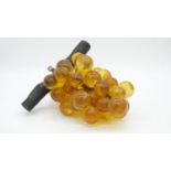 A vintage bunch of amber lucite grapes mounted on a wooden branch. H.18cm
