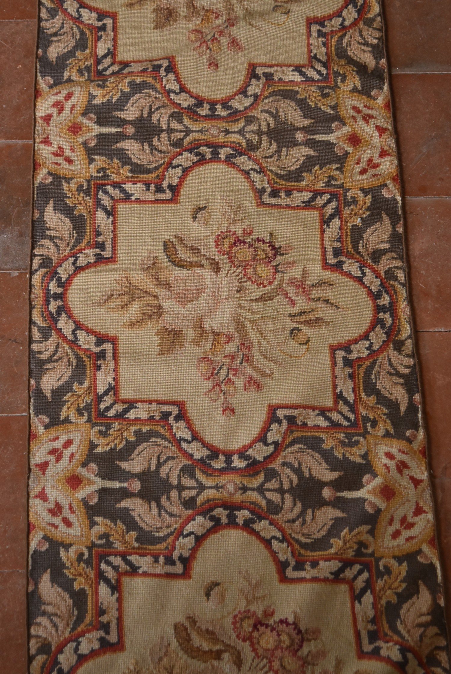 A needlepoint runner with repeating floral spray medallions on a foliate ground. L.420 W.57cm