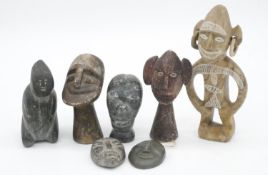 A collection of seven carved hardstone tribal figures, two of faces with hanging loops. H.16cm